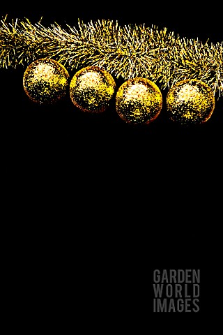 FOUR_YELLOW_CHRISTMAS_BALLS_HANGING_AGAINST_A_BLACK_BACKGROUND
