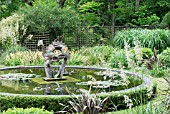 DRAGON SCULPTURE BY SUSAN FORD (WITH ST. DUNSTAN AS PART OF THE SCULPTURE) IN THE DRAGON GARDEN,  KNOLL GARDENS,  HAMPRESTON,  DORSET: EARLY JUNE.