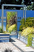 A VIEW IN A GARDEN OF CONTRASTS DESIGNED BY DIZZY SHOEMARK,  RHS WISLEY: AUGUST. PHORMIUM BRONZE BABY REFLECTED IN MIRROR.