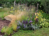 JORDANS WILDLIFE GARDEN DESIGNED BY SELINA BOTHAM. NATURAL PLANTING WITH SCULPTURED STRAW BENCH