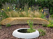 JORDANS WILDLIFE GARDEN DESIGNED BY SELINA BOTHAM. NATURAL PLANTING WITH SCULPTURED STRAW BENCH