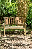 WOODEN GARDEN BENCH ON A GRAVEL PATH